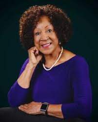 female African American professional with blue shirt and pearl necklace poses and smiles for camera
