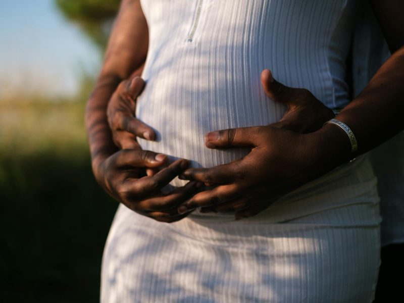 hands of a couple embracing the baby inside her growing belly