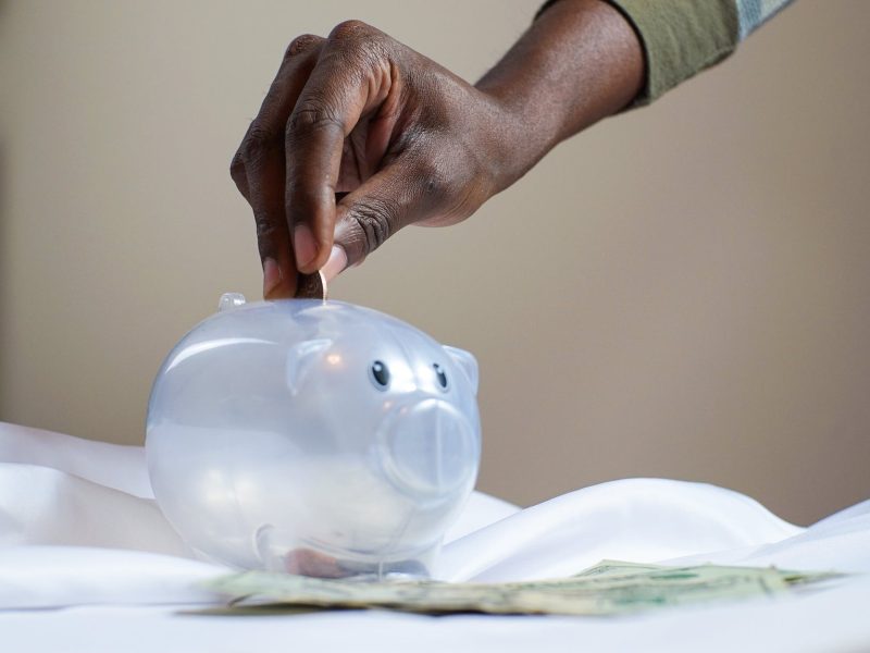 person putting coin in a piggy bank
