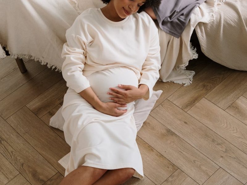 pregnant woman in white long sleeve dress sitting on the floor